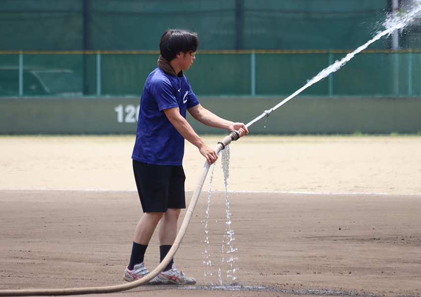 グラウンドに水をまく硬式野球部員